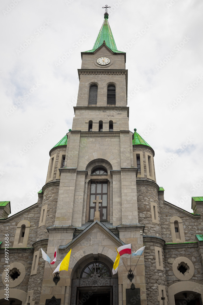 Tall church in a tourist town. Concrete facade and moisture of Poland. Chapel with a green roof. Tall church in a tourist town. Concrete facade and moisture of Poland. Chapel with a green roof.