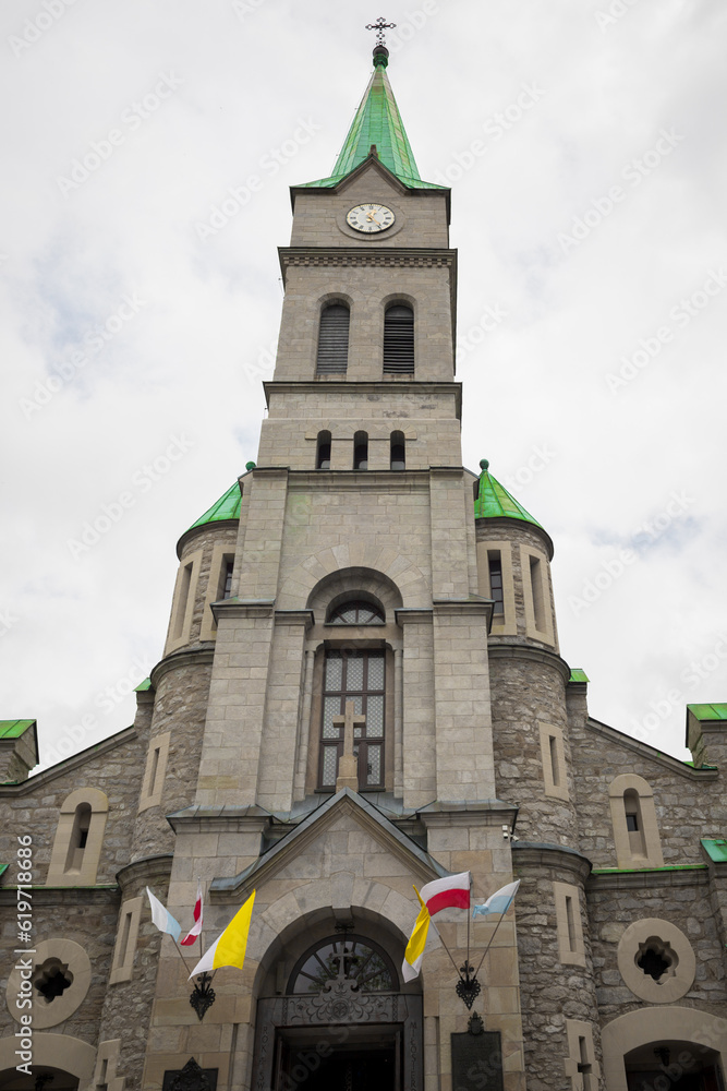 Tall church in a tourist town. Concrete facade and moisture of Poland. Chapel with a green roof.