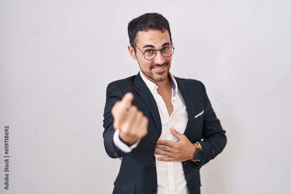 Handsome business hispanic man standing over white background beckoning come here gesture with hand inviting welcoming happy and smiling Handsome business hispanic man standing over white background beckoning come here gesture with hand inviting welcoming happy and smiling