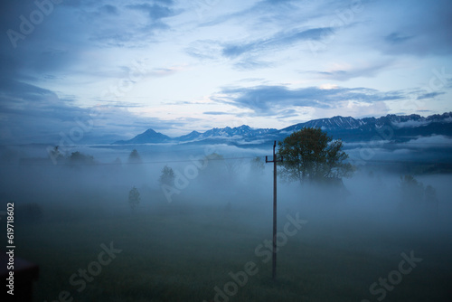Cloudy weather in the mountains. Tatras in clouds and fog. Clouds float below the mountain peaks. Trees in the clouds. View from the height of the villa, located at an altitude of 1100 meters.