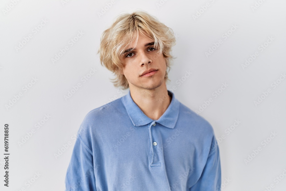 Young modern man standing over isolated background relaxed with serious expression on face. simple and natural looking at the camera. Young modern man standing over isolated background relaxed with serious expression on face. simple and natural looking at the camera.