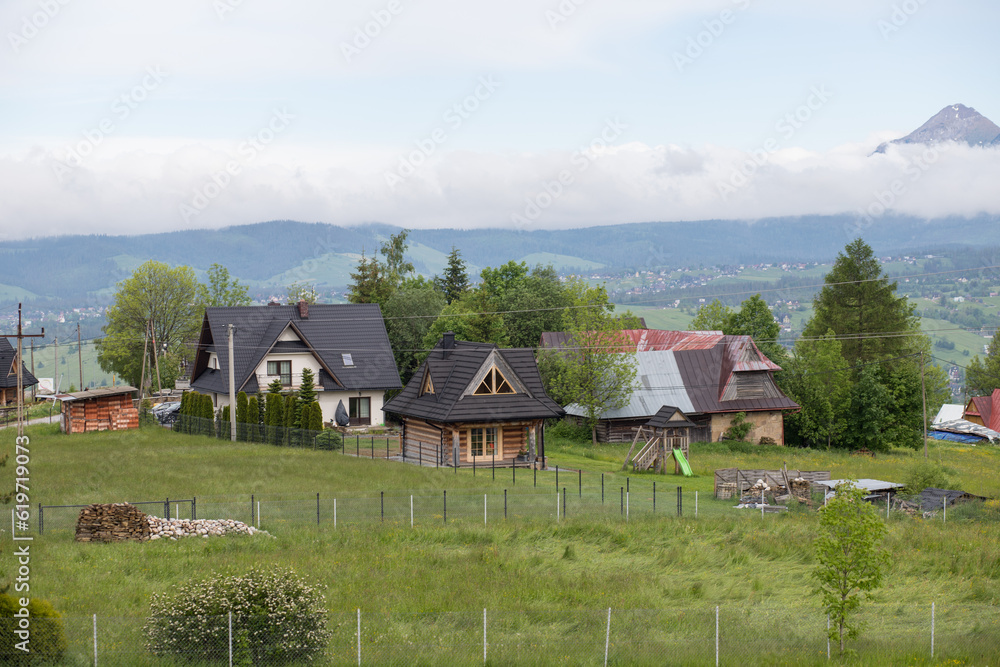 Houses located in a panoramic position with views of the mountain range. Houses in the Tatra mountains. Green meadows with small houses.