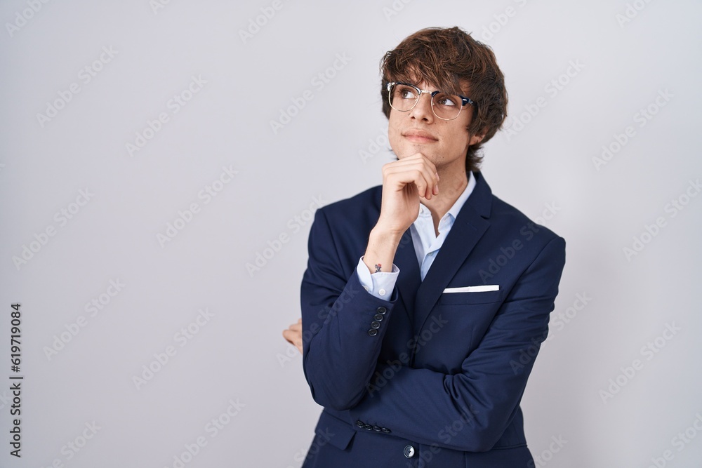 Hispanic business young man wearing glasses with hand on chin thinking about question, pensive expression. smiling with thoughtful face. doubt concept. Hispanic business young man wearing glasses with hand on chin thinking about question, pensive expression. smiling with thoughtful face. doubt concept.