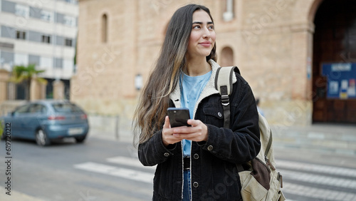 Young beautiful hispanic woman student smiling confident using smartphone at street
