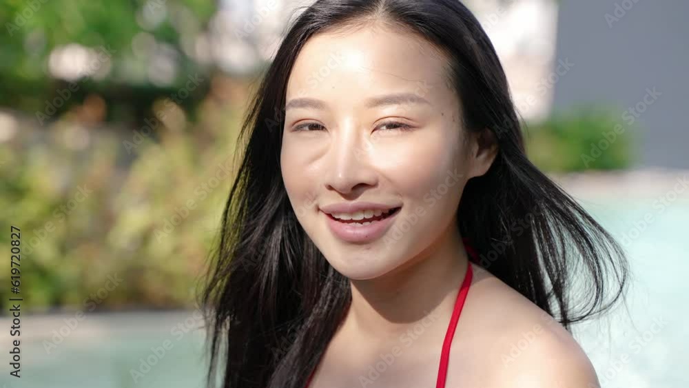 Young Asian woman with black hair in bikini smiling by pool Young Asian woman with black hair in bikini smiling by pool