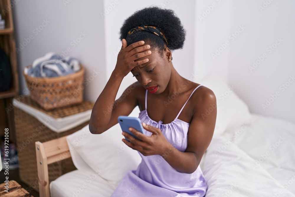African american woman using smartphone with serious expression at bedroom African american woman using smartphone with serious expression at bedroom