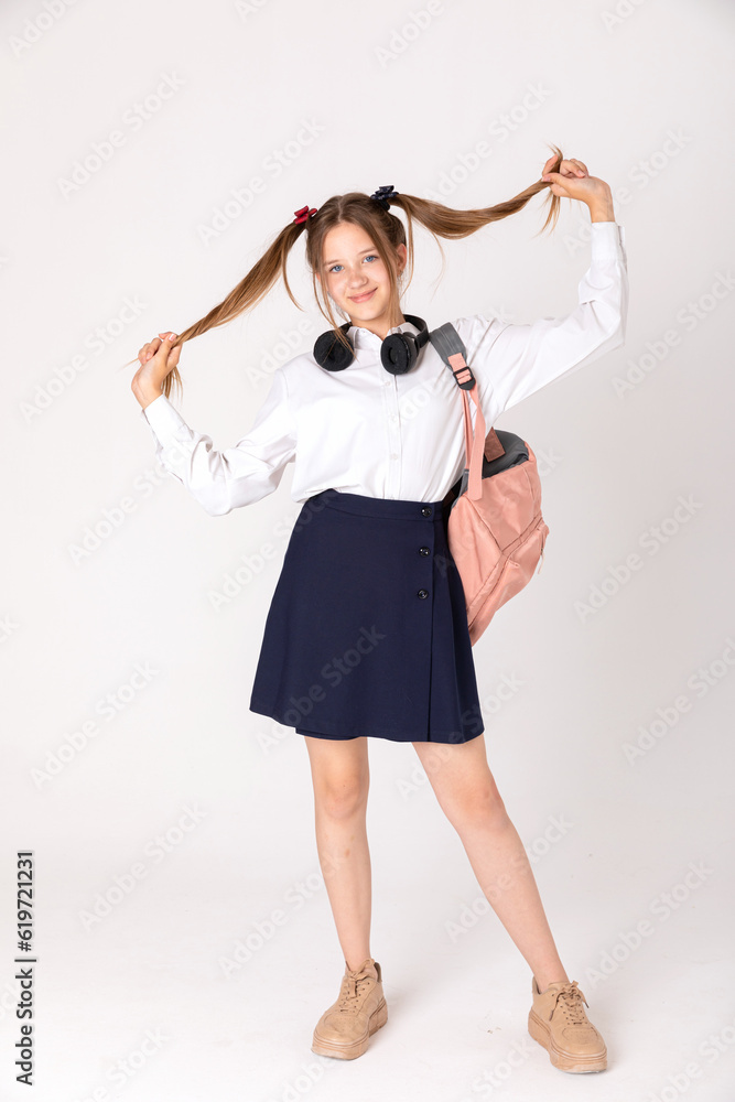 Charming young school girl on white studio backdrop. Joyful schoolgirl dancing smiles wide. Happy teenager loves music. Mockup, youth. Charming young school girl on white studio backdrop. Joyful schoolgirl dancing smiles wide. Happy teenager loves music. Mockup, youth.