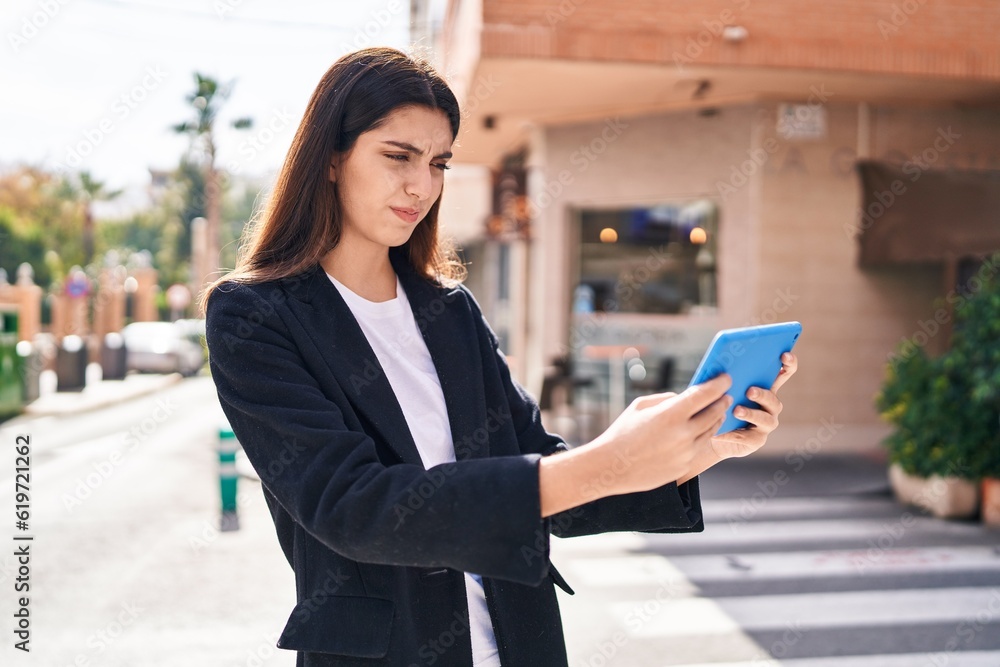 Young beautiful hispanic woman using touchpad with serious expression at street Young beautiful hispanic woman using touchpad with serious expression at street
