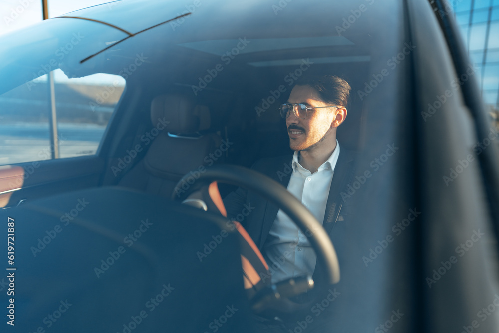 Naklejka premium Young businessman in elegant suit driving luxury car