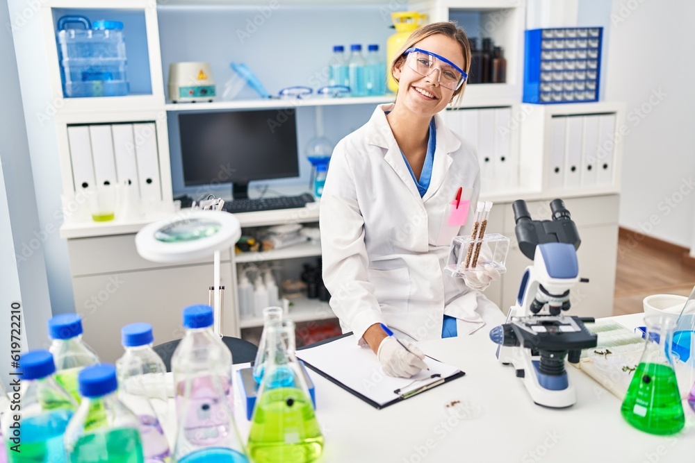 Young hispanic woman scientist write on document holding test tubes at laboratory Young hispanic woman scientist write on document holding test tubes at laboratory