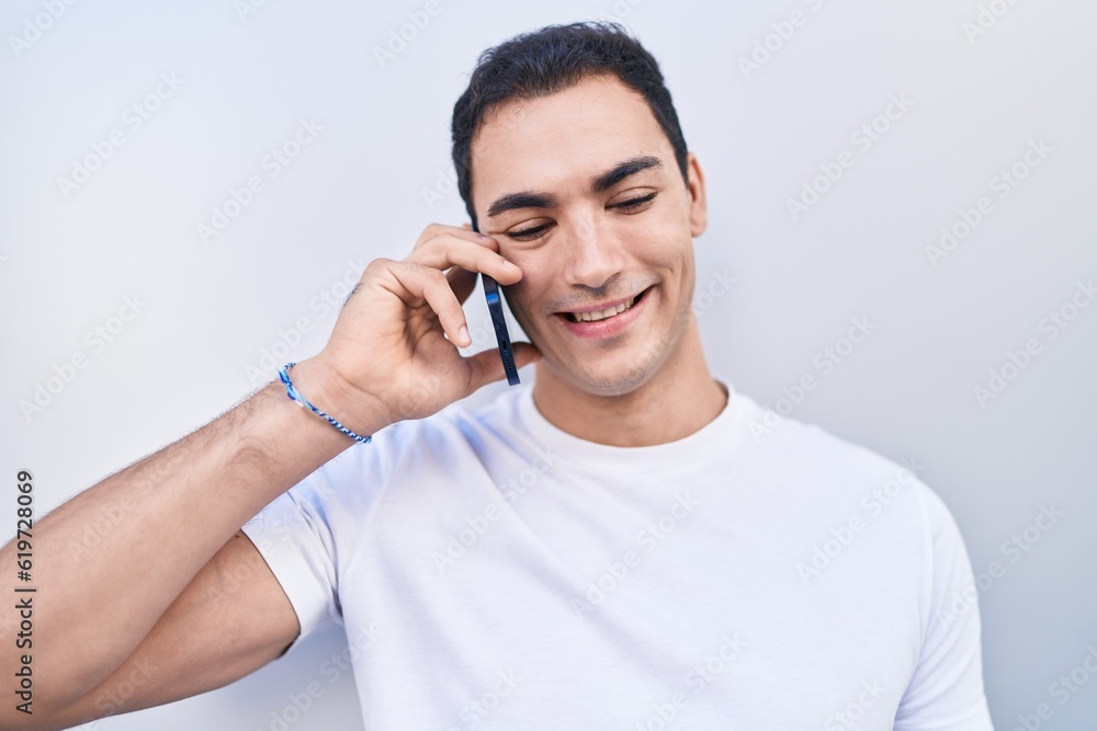 Young hispanic man smiling confident talking on the smartphone over isolated white background Young hispanic man smiling confident talking on the smartphone over isolated white background