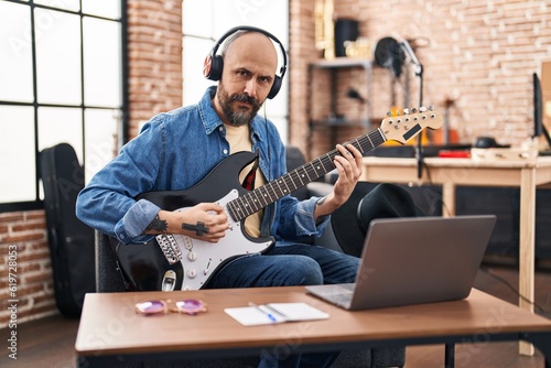 Tela Young bald man musician having online electrical guitar lesson at music studio