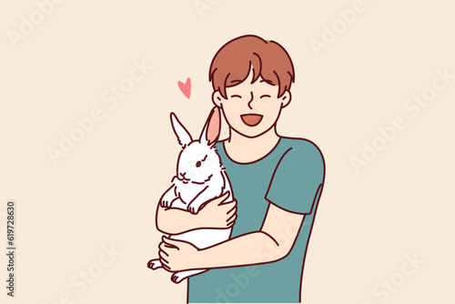 Boy with little rabbit laugh hugging beloved pet for concept of love for domestic animals. Happy child with white eared rabbit for advertising pet store with goods for pets and their owners