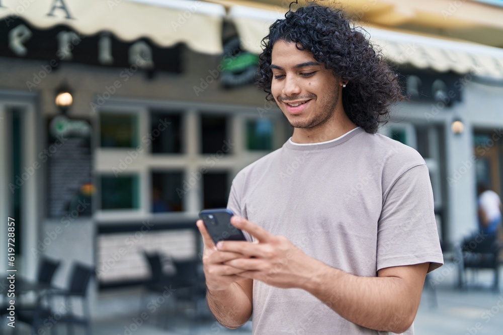 Young latin man smiling confident using smartphone at coffee shop terrace Young latin man smiling confident using smartphone at coffee shop terrace