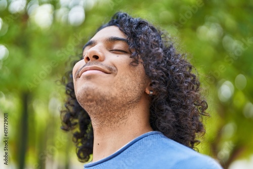 Young latin man breathing with closed eyes at park