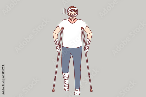 Ill man with bandages on hands and head uses walking aids after being involved in car accident. Guy injured in car accident needs long-term treatment and rehabilitation to restore health