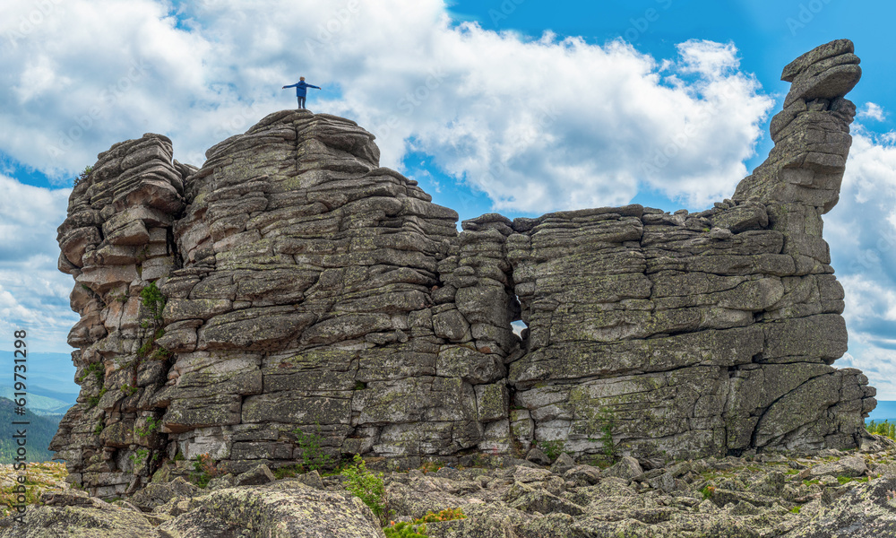 Fototapeta premium The person climbed to the top of the stone cliff and spreading arms.