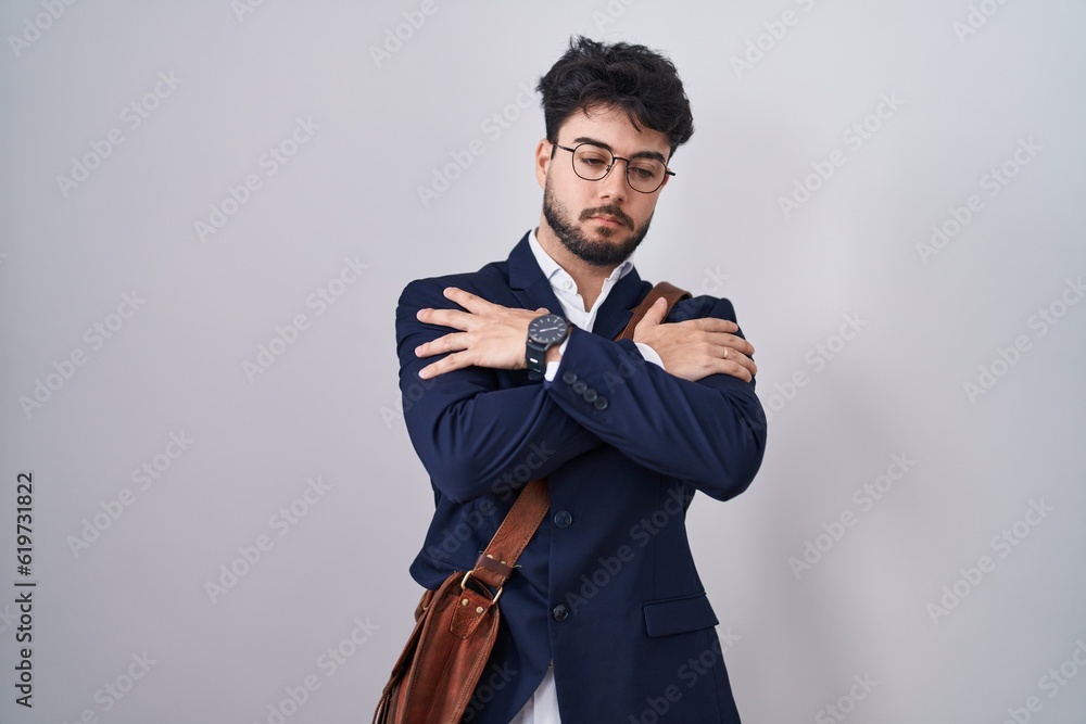 Hispanic man with beard wearing business clothes hugging oneself happy and positive, smiling confident. self love and self care Hispanic man with beard wearing business clothes hugging oneself happy and positive, smiling confident. self love and self care