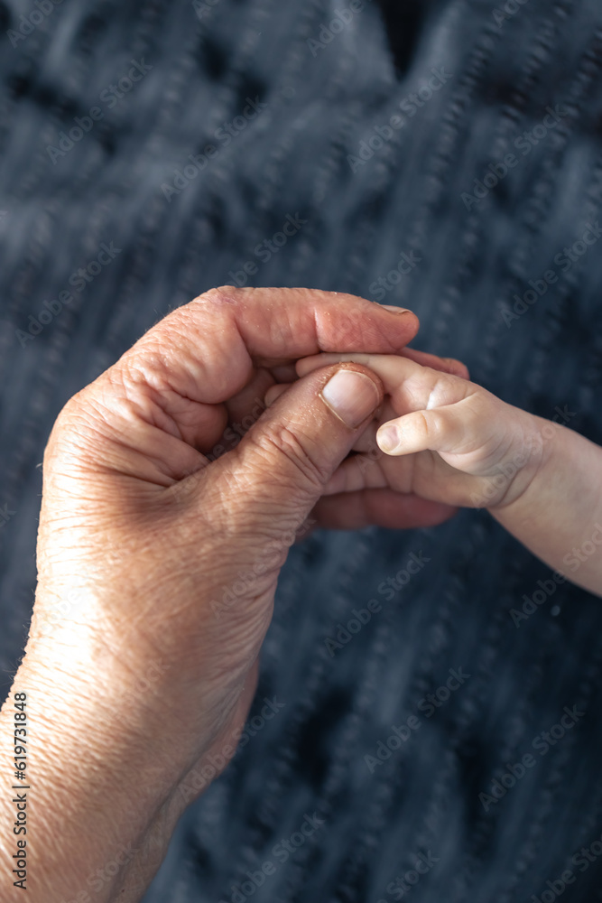 Hands of senior person and little baby close up.