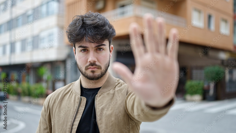 Young hispanic man doing stop gesture with hand at street Young hispanic man doing stop gesture with hand at street