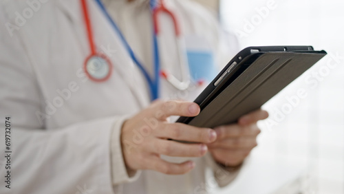 Young hispanic man doctor using touchpad at clinic