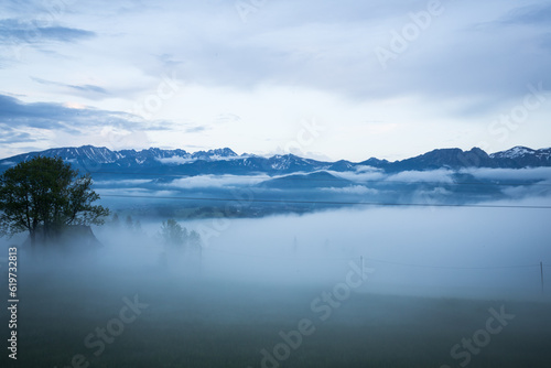 Mountains and tree tops in the clouds. Cloudy weather in the mountains. Mountain view from the villa. Clear blue sky and floating clouds at camera level.