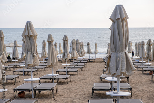 Beach in Antalya, Turkiye. Umbrellas and sun loungers in the assembled state on the beach. © Анатолий Савицкий
