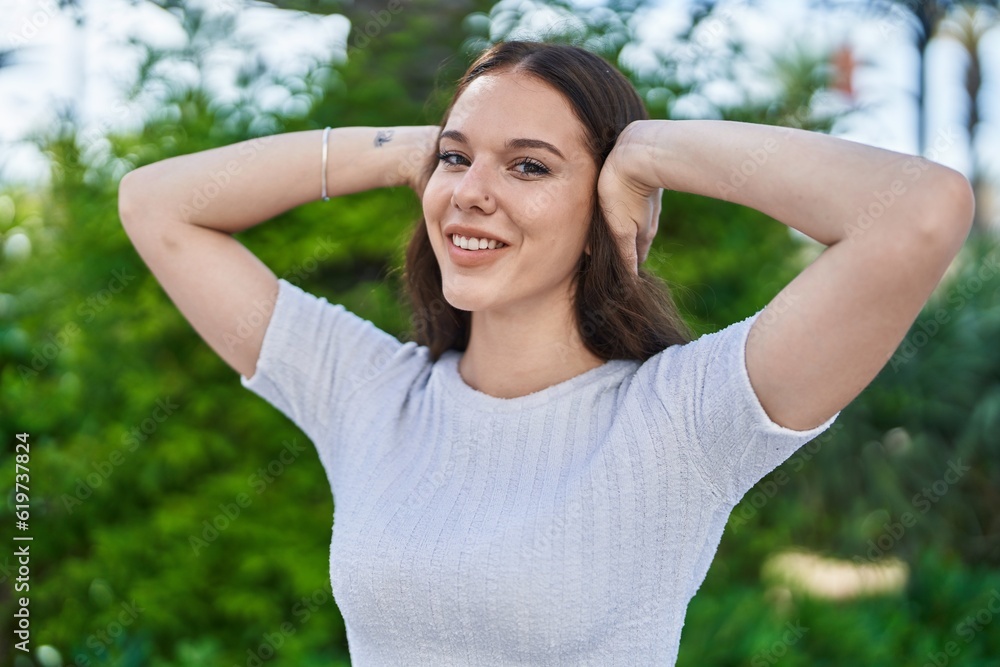Young woman smiling confident with hands on ears at park