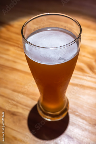 A glass of beer close-up high angle view on a wooden table in a bar