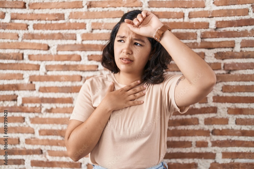 Young hispanic woman standing over bricks wall touching forehead for illness and fever, flu and cold, virus sick Young hispanic woman standing over bricks wall touching forehead for illness and fever, flu and cold, virus sick