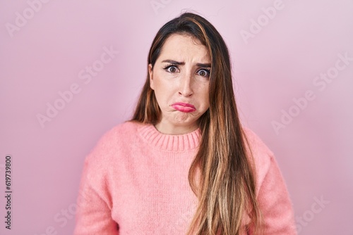 Young hispanic woman standing over pink background depressed and worry for distress, crying angry and afraid. sad expression.