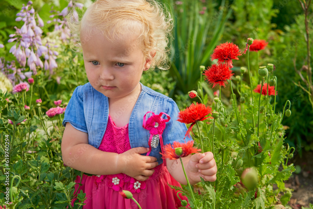 beautiful little girl in flowers,adorable thoughtful happy baby girl stands in the garden among the flowers