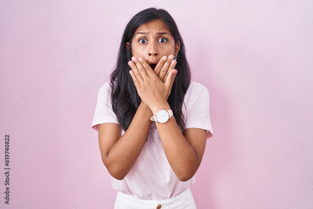 Young hispanic woman standing over pink background shocked covering mouth with hands for mistake. secret concept. Young hispanic woman standing over pink background shocked covering mouth with hands for mistake. secret concept.