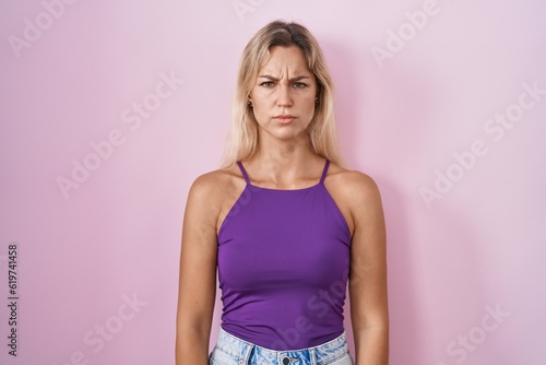 Young blonde woman standing over pink background skeptic and nervous, frowning upset because of problem. negative person.