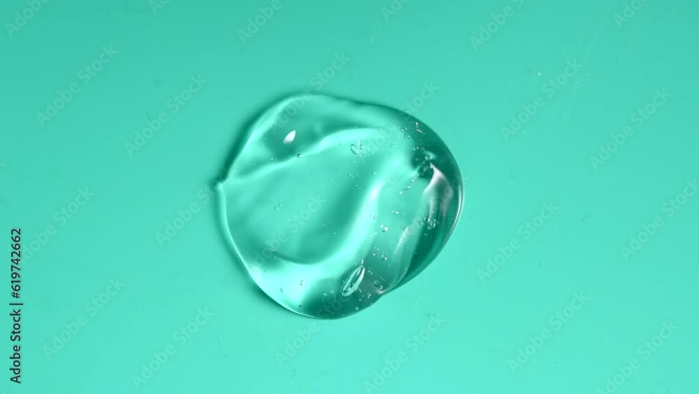 Transparent gel drop. Liquid cream gel cosmetic smudge texture on blue background. Cosmetics serum gel, hyaluronic acid cream background, facial treatment closeup Transparent gel drop. Liquid cream gel cosmetic smudge texture on blue background. Cosmetics serum gel, hyaluronic acid cream background, facial treatment closeup