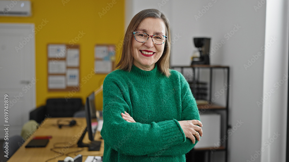 Fototapeta premium Mature hispanic woman with grey hair smiling confident with crossed arms at office