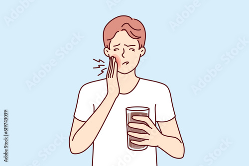 Man suffers from toothache caused by cold drink and needs pain medication and dentist. Guy with toothache associated with caries or stomatitis holds glass of medicine for mouthwash.