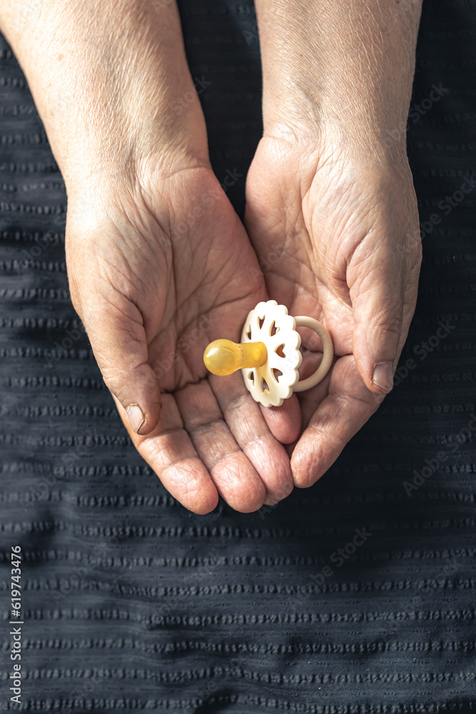 Close-up, a baby pacifier in the hands of a grandmother. Close-up, a baby pacifier in the hands of a grandmother.
