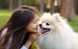 Girl lying on the grass in the park with a pomeranian spitz