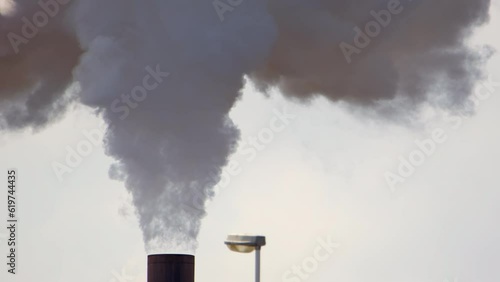 Telephoto shot of smokestack emitting harmful greenhouse gases into atmosphere photo