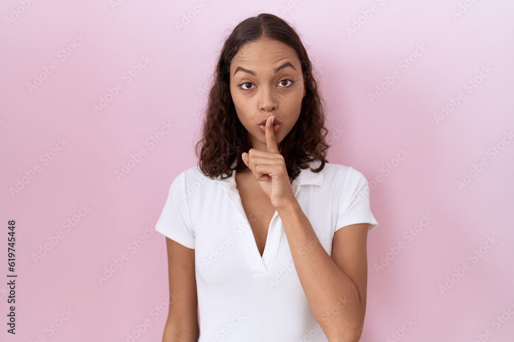 Young hispanic woman wearing casual white t shirt asking to be quiet with finger on lips. silence and secret concept. Young hispanic woman wearing casual white t shirt asking to be quiet with finger on lips. silence and secret concept.