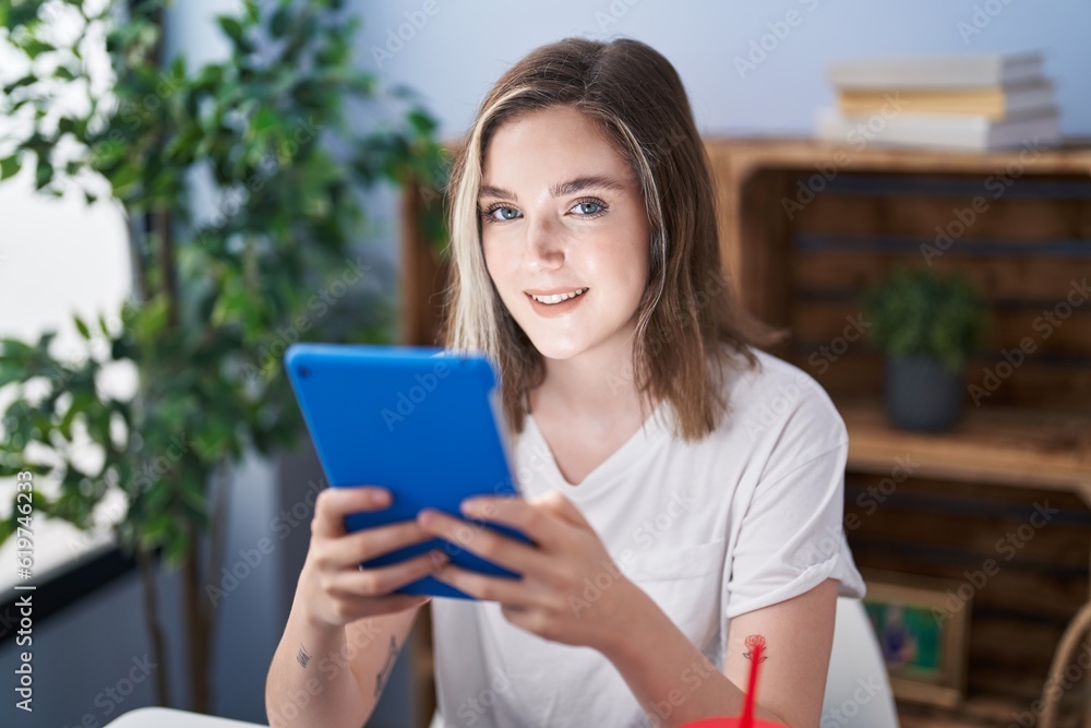 Young woman using touchpad sitting on table at home Young woman using touchpad sitting on table at home