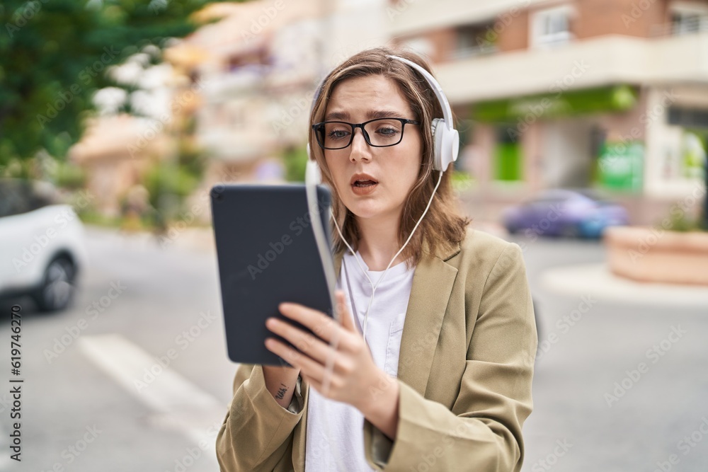 Young woman business worker using touchpad and headphones at street Young woman business worker using touchpad and headphones at street