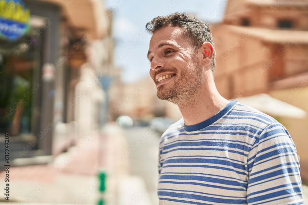 Young hispanic man smiling confident looking to the side at street