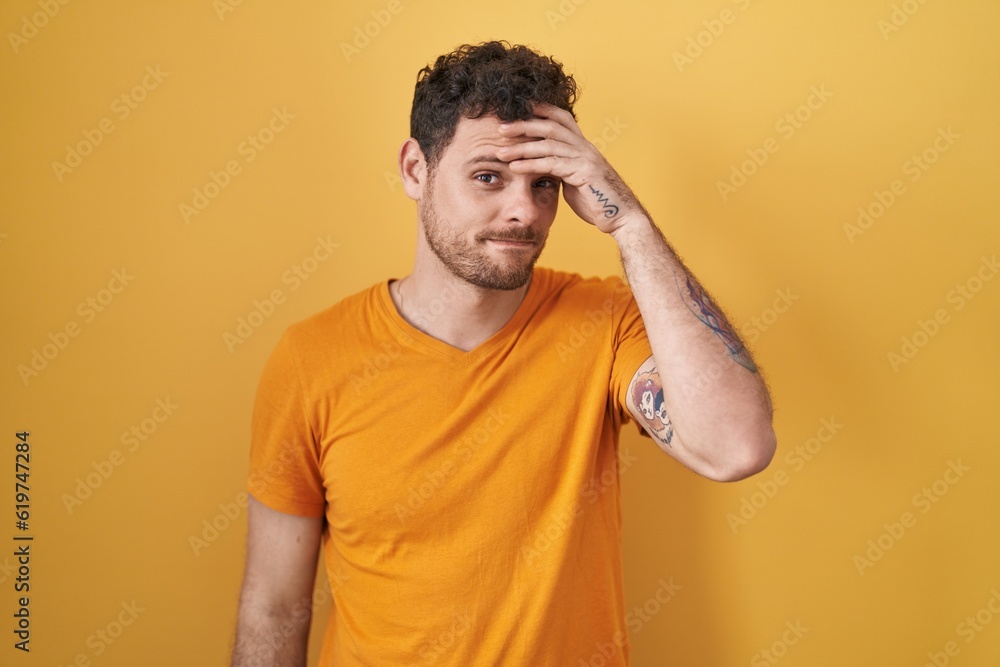 Young hispanic man standing over yellow background worried and stressed about a problem with hand on forehead, nervous and anxious for crisis Young hispanic man standing over yellow background worried and stressed about a problem with hand on forehead, nervous and anxious for crisis