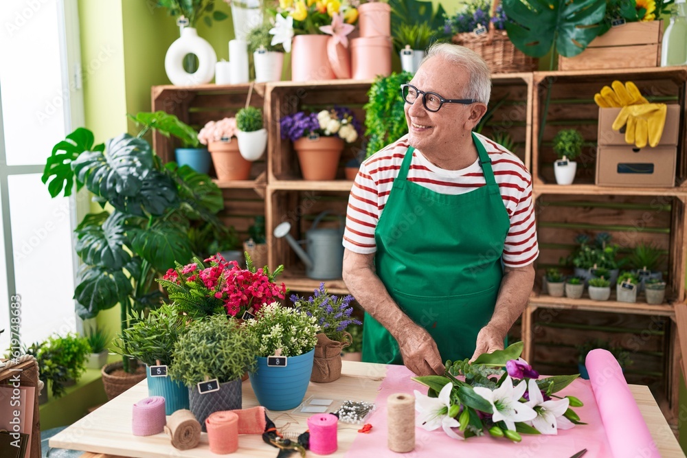 Middle age grey-haired man florist make bouquet of flowers at flower shop Middle age grey-haired man florist make bouquet of flowers at flower shop