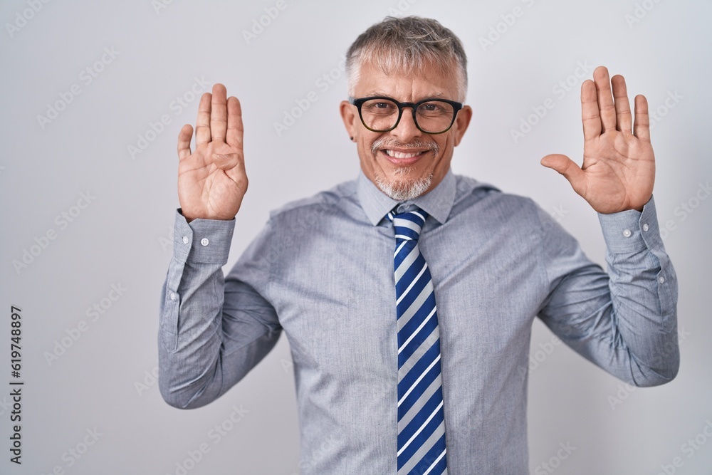 Hispanic business man with grey hair wearing glasses showing and pointing up with fingers number nine while smiling confident and happy.