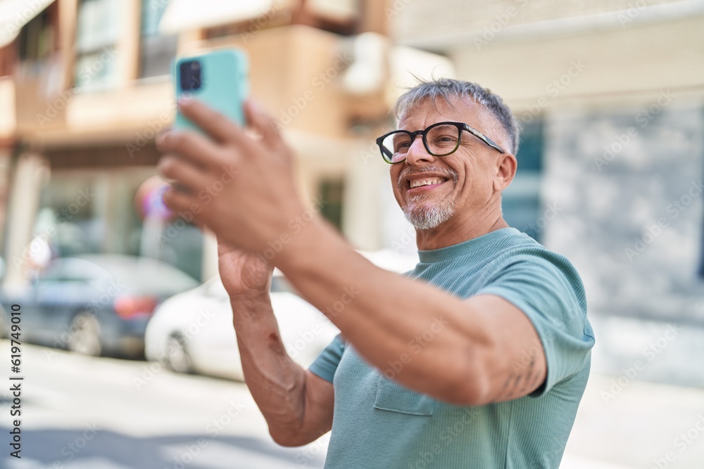 Middle age grey-haired man smiling confident having video call at street Middle age grey-haired man smiling confident having video call at street