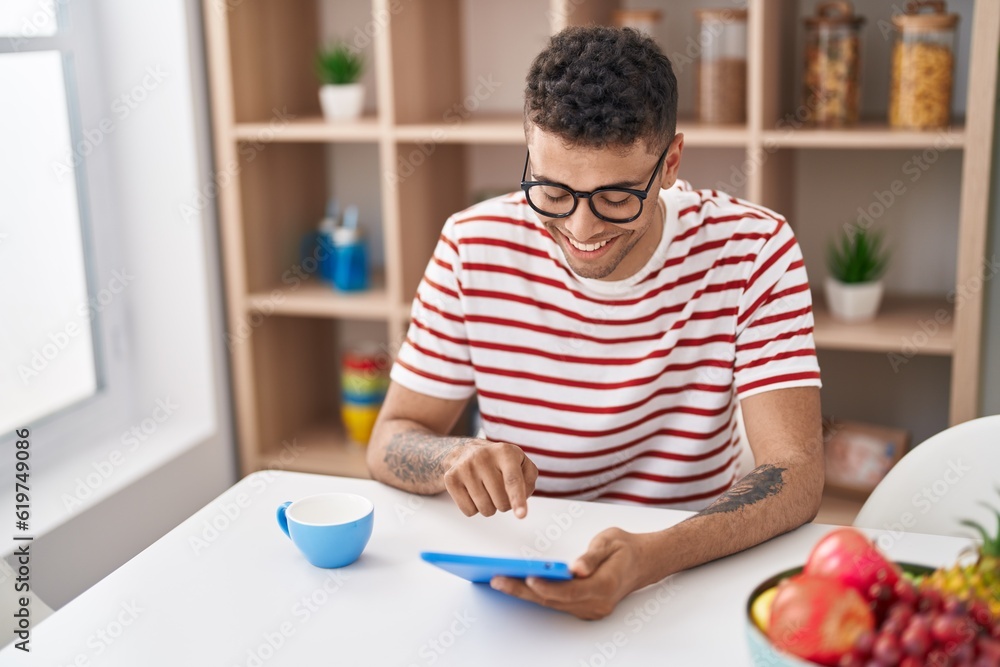 African american man using touchpad drinking coffee at home African american man using touchpad drinking coffee at home