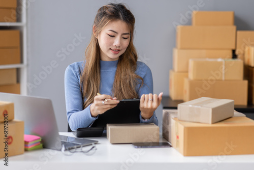 Portrait of asian young freelancer small business startup, SME owner, asian female entrepreneur work and check orders online at home. online SME business idea.